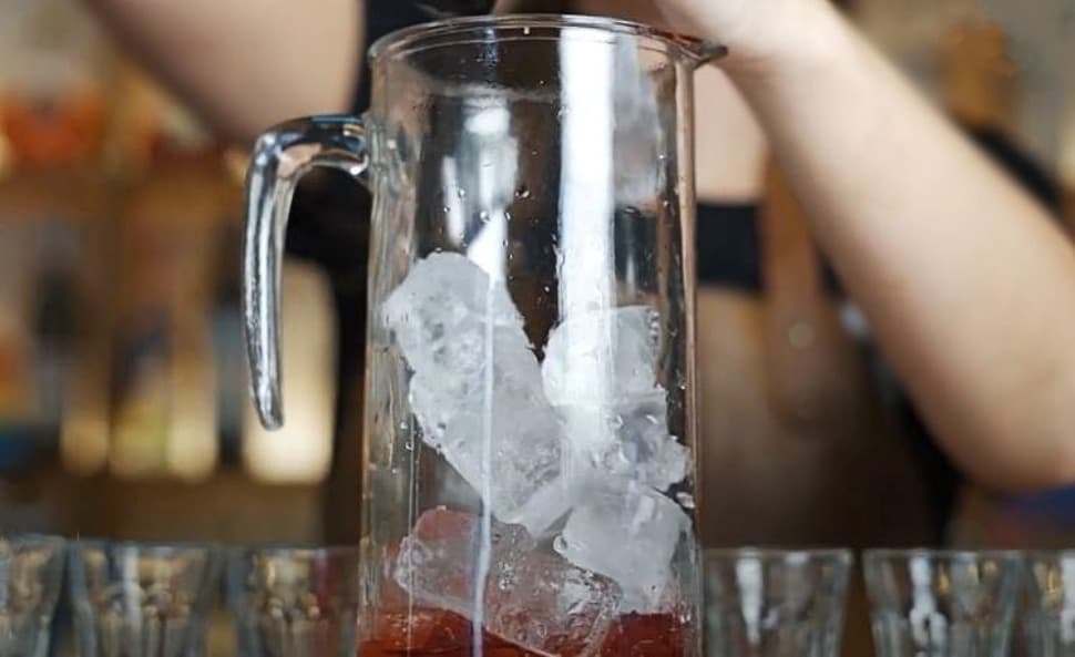 Bartender putting ice into a jug with grenadine Bartender putting ice into a jug with grenadine