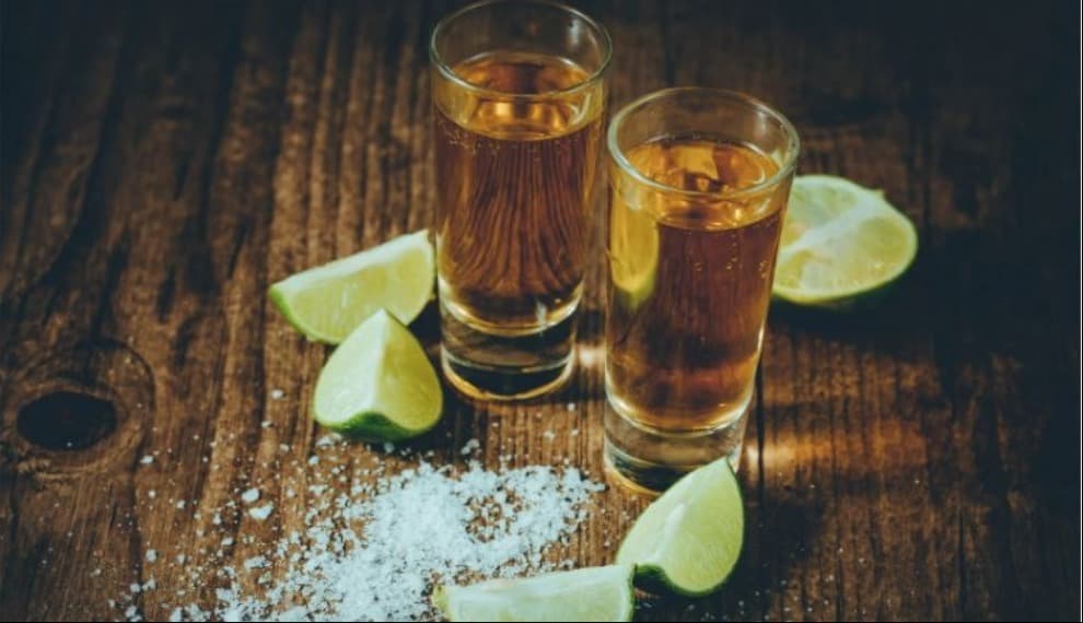 Two gold tequila shots with salt and lime wedges Two gold tequila shots with salt and lime wedges